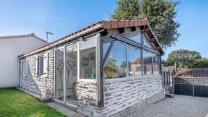 A small, stone-clad building with a glass enclosure, a tiled roof, and a gravel driveway. - 500 m from the beach, garden, 4 adults 1 child (Saint-Michel-Chef-Chef)