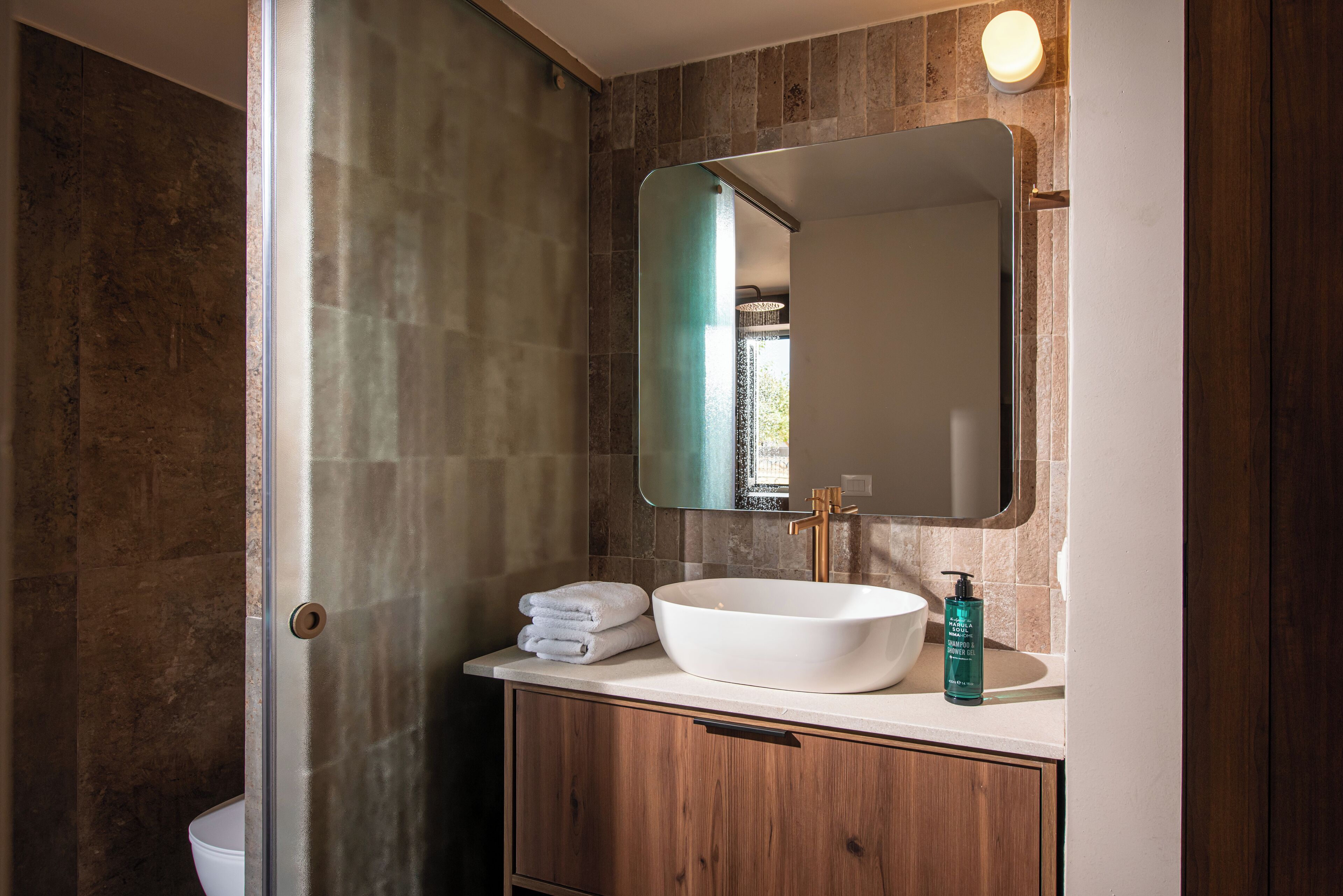 A bathroom with a white sink, a large mirror, and a wooden cabinet.