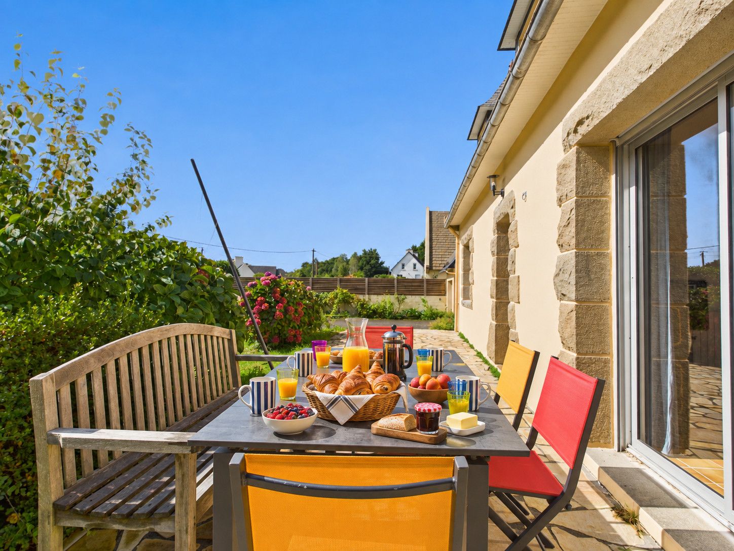 An outdoor dining area with a table set for breakfast, including fruits, pastries, and beverages.