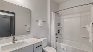 A modern bathroom with a sink, toilet, and shower area.