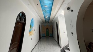 Un pasillo con un mural de pájaros volando en el cielo, paredes blancas y suelo de mármol.