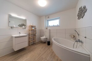 A modern bathroom with a sink, toilet, and bathtub.