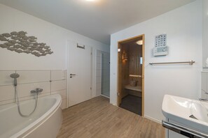 Moderni kylpyhuone, jossa on kylpyamme, suihku ja wc.