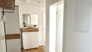A modern kitchen with white cabinets, a wooden countertop, and a mirror above the sink. - North Sea apartment with sauna & south-facing balcony - sea breeze and beach just 200 m away (Nordseeheilbad Schillig)