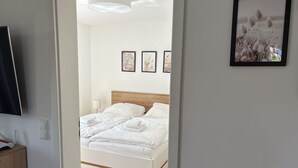 A hotel room with a bed, a TV, and framed pictures on the wall. - North Sea apartment with sauna & south-facing balcony - sea breeze and beach just 200 m away (Nordseeheilbad Schillig)