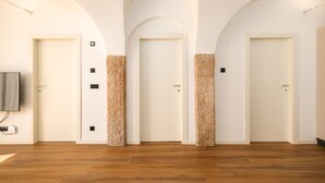 Un pasillo con tres puertas, suelo de madera y un televisor montado.