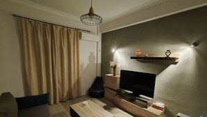 Un salon moderne doté d’un téléviseur à écran plat, de meubles en bois, d’un canapé, d’une table basse et d’une étagère décorative.