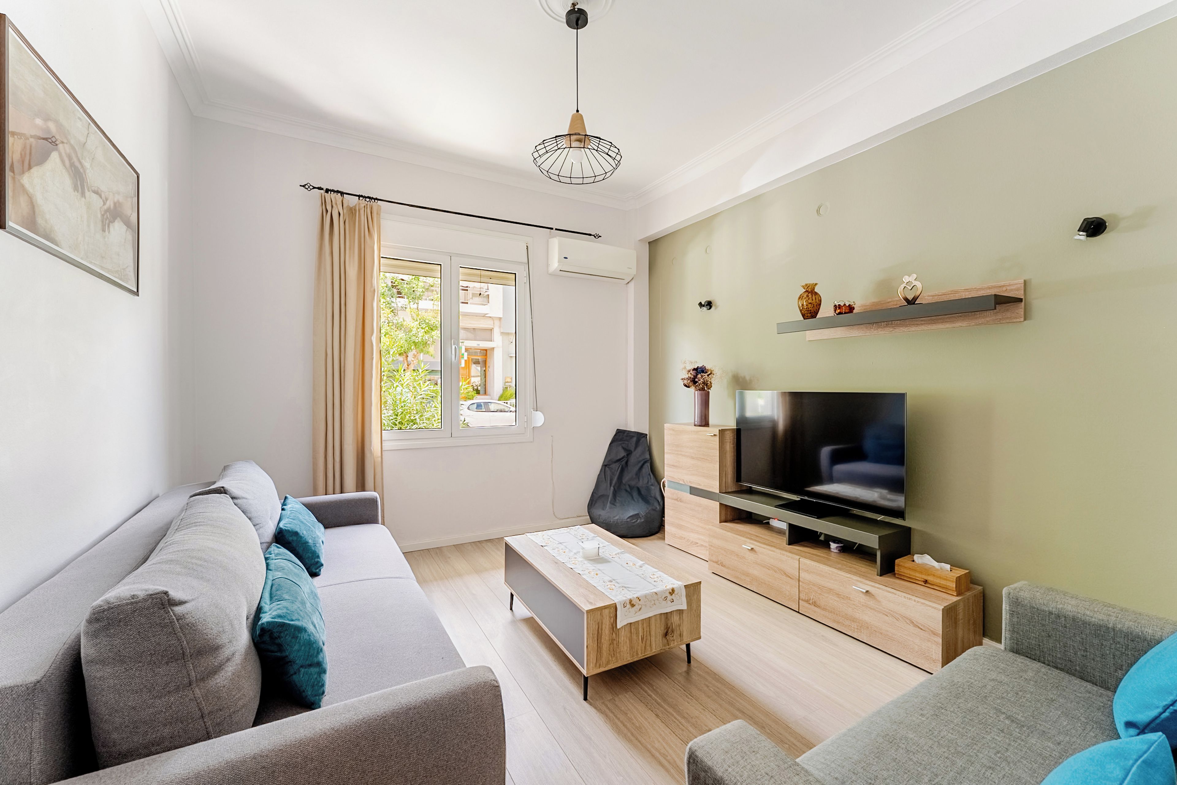 A modern living room with a sofa, a coffee table, a TV, and a window with curtains.