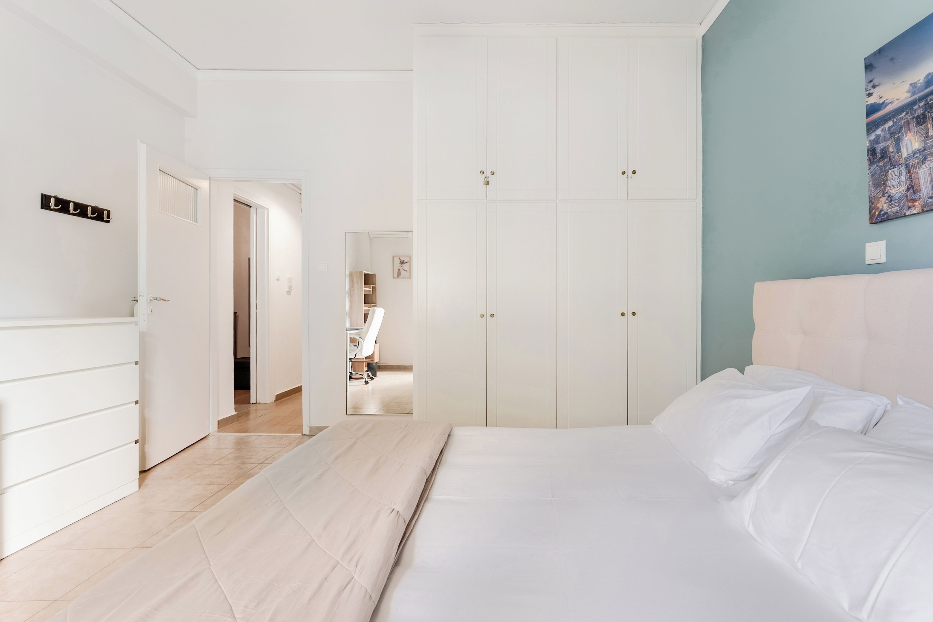 A hotel room with a bed, a wardrobe, and a desk.