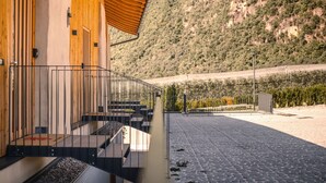 A modern building with a wooden facade, a metal staircase, and a paved area leading to a gate. - Apartment 'Maso Renner Quadrilocale Torre' with Mountain View, Shared Garden and Wi-Fi (Laives)