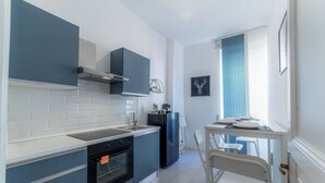 Eine moderne Küche mit weißen und blauen Schränken, einem eingebauten Backofen und einem Essbereich mit Tisch und Stühlen.