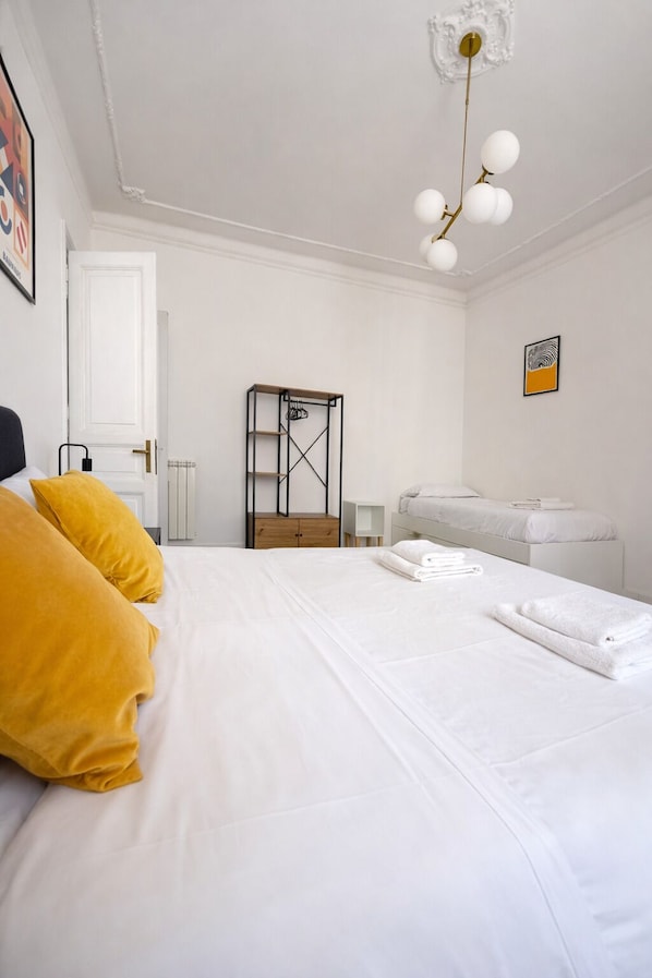 A bedroom with a bed, white bedding, a wooden nightstand, a white dresser, a hanging light fixture, and a framed picture on the wall. - 3 Wonderful Apartments Palumbo to Vatican Museums (Roma)