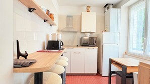 A compact kitchen with white cabinets, a built-in oven, and a coffee machine.
