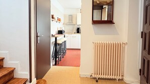A hallway leading to a kitchen with a radiator and a mirror on the wall.