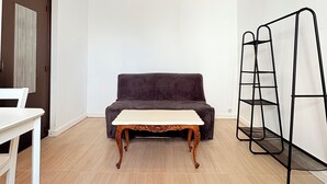 A room with a dark-colored sofa, a white table, and a black metal shelf unit.