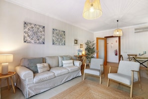 Een woonkamer met een bank, twee fauteuils, een salontafel, een lamp en wanddecoratie.