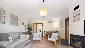A living room with a sofa, chairs, a fireplace, and a dining area. - Apartment 'Do Vale Holidays' with Shared Pool, Wi-Fi and Air Conditioning (Guia)