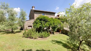 A stone building with a tiled roof, surrounded by a grassy area and trees.