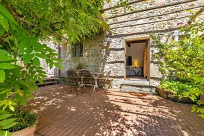 A stone building with a wooden door, a brick patio, and outdoor seating.