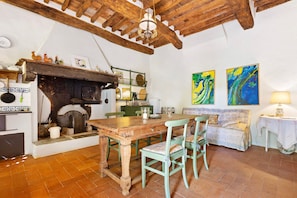 A rustic kitchen with a wooden table, chairs, a fireplace, and a dining area.