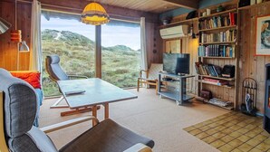 A cozy living room with a wooden interior, a dining table, a TV, and a bookshelf filled with books. - "Asel" - 1km from the sea by Interhome (Fanø)
