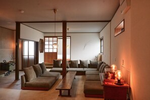 Uma sala de estar moderna com um sofá de canto, um banco de madeira e iluminação pendente.