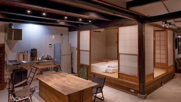 Une pièce de style japonais traditionnel, avec un sol recouvert de tatamis, une petite table en bois et un futon servant de lit.