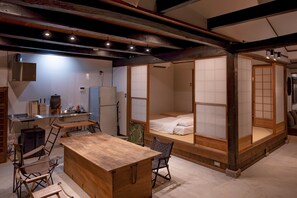 Um quarto em estilo tradicional japonês, com tatames no chão, uma mesa de madeira baixa e um futon.