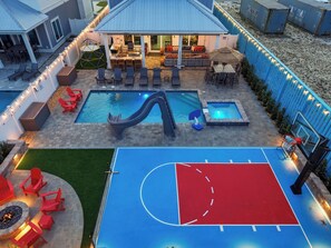 Un área de piscina con tobogán, asientos y una cancha de baloncesto.