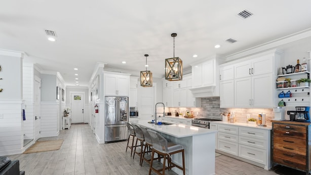 A modern kitchen with white cabinetry, a central island with bar stools, stainless steel appliances, and pendant lighting. - 5 Kings-Private Backyard Oasis, Pool/Spa/Turbo Slide-Beach (Panama City Beach)