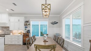 A spacious kitchen with white cabinetry, a wooden dining table, and a large window with blinds. - 5 Kings-Private Backyard Oasis, Pool/Spa/Turbo Slide-Beach (Panama City Beach)