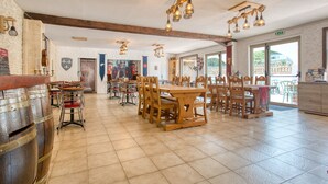 Een ruim restaurant met houten tafels en stoelen, zichtbare balken en hangende lampen.