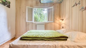 Een slaapkamer met een bed, een raam, een radiator en een wandlamp.