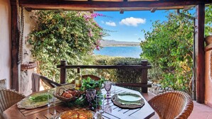 A wooden table set for dining with a view of a body of water and mountains in the background.