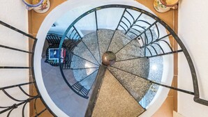 Un escalier en colimaçon doté d’un pilier central, de rampes en métal et d’un sol carrelé.