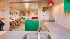 Una cocina con paredes de madera, una isla verde y una lámpara colgante roja.