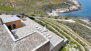 A rooftop terrace with stone flooring, a small building, and a view of the coastline. - Clio Apartment Kea (Otzias)