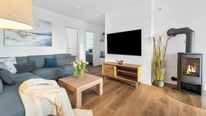 Uma sala de estar moderna com sofá, mesa de centro, televisão e lareira a lenha.