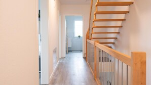 Un intérieur moderne avec un escalier en bois et un couloir menant à une cuisine.