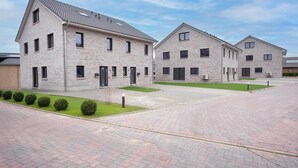 Un bâtiment moderne avec une façade en briques, de nombreuses fenêtres et une allée pavée.