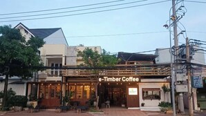 Ein Café namens e-Timber Coffee mit Außenbestuhlung und einer sichtbaren Schaufensterfront.