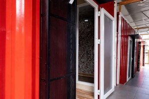 A corridor with a red wall and a door leading to a room with patterned wallpaper. - Nin Garden Homestay (Vung Tau)