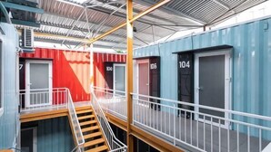 Ein mehrgeschossiges Hotel mit Metallbedachung, Treppen und nummerierten Türen.