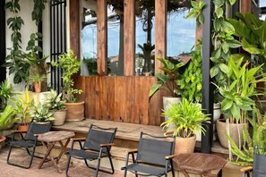 An outdoor seating area with potted plants, wooden furniture, and a wooden fence. - Nin Garden Homestay (Vung Tau)