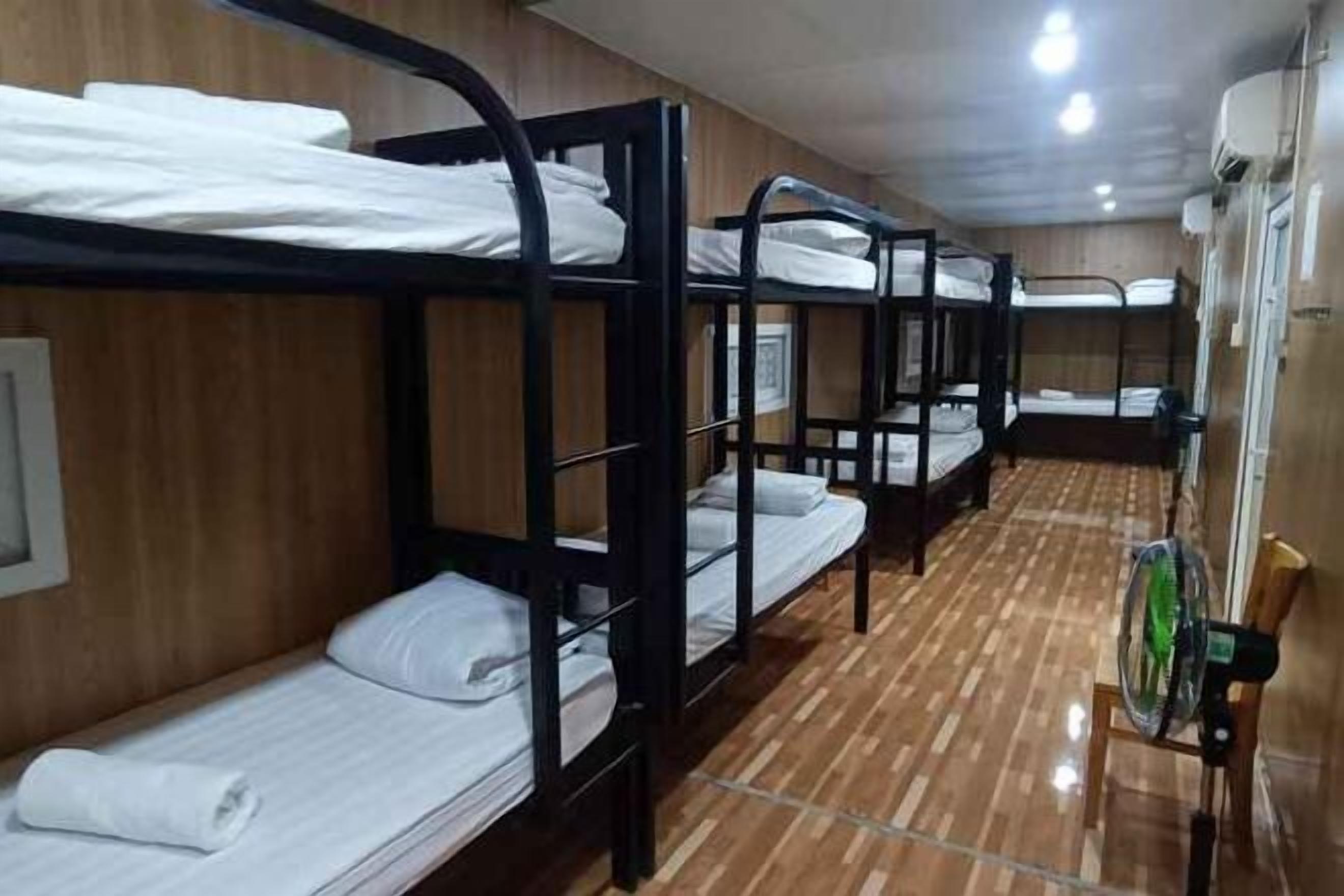 A row of bunk beds in a room with wooden walls and a tiled floor.
