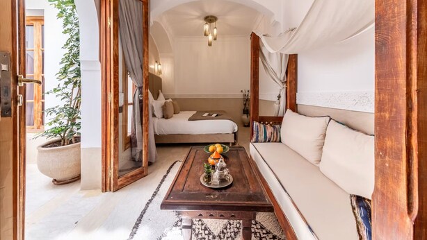 A cozy bedroom with a bed, a sofa, a coffee table, and a potted plant. - Superior Room Oasis (Marrakesh)