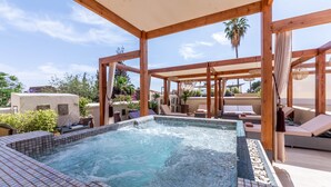 Un área de piscina en la azotea con suelo de baldosas, pérgolas de madera y sillones de descanso.