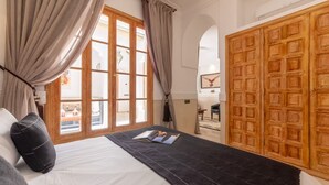 Un dormitorio con una cama grande, una ventana con cortinas y un armario de madera.