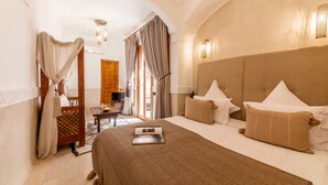 A hotel room with a large bed, a desk with a laptop, and a view of the outdoors through a window. - Entire Medina Riad with Rooftop & pool (Marrakesh)
