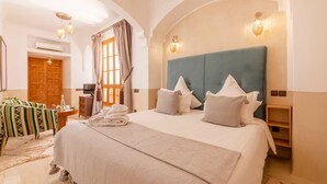 Ein Hotelzimmer mit einem großen Bett, einem Holzschrank, einem Schreibtisch mit Stuhl und einem fenster mit Vorhängen.
